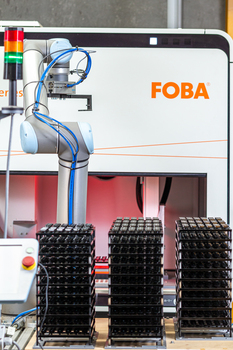 Industrieroboter vor FOBA-Lasermarkiersystem mit gestapelten Bauteilen.jpg